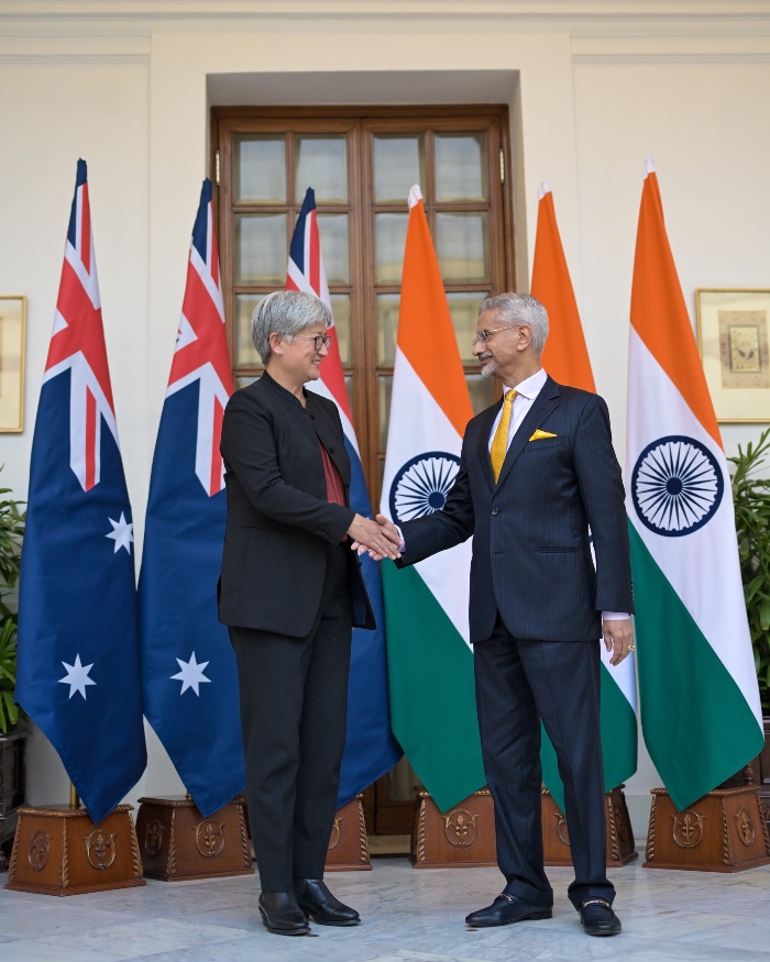 woman and man in suits with standing next to flags