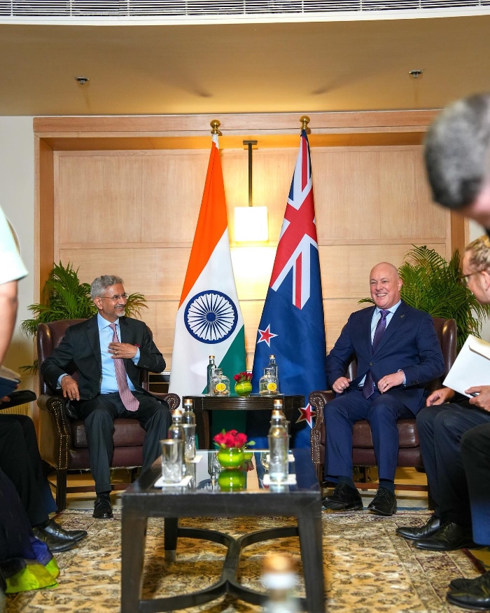 men in suits sitting and flags of india and New Zealand