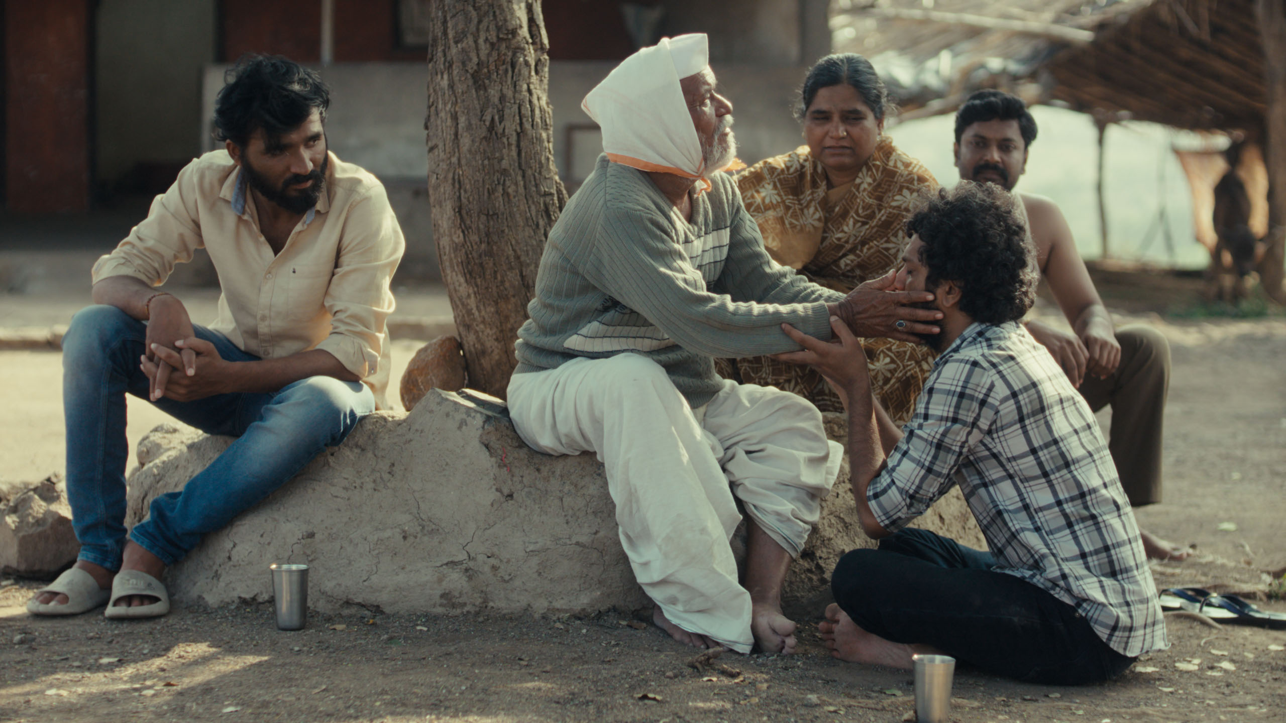 Four men and a woman sitting under a tree.